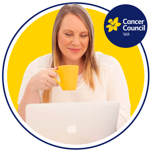 Lady holding mug and working on a computer, smiling.