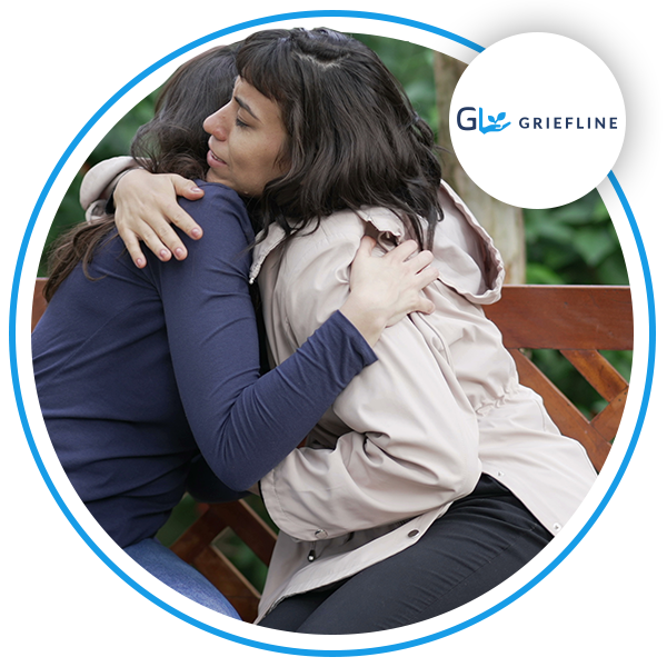 Two people hugging whilst sitting on a bench