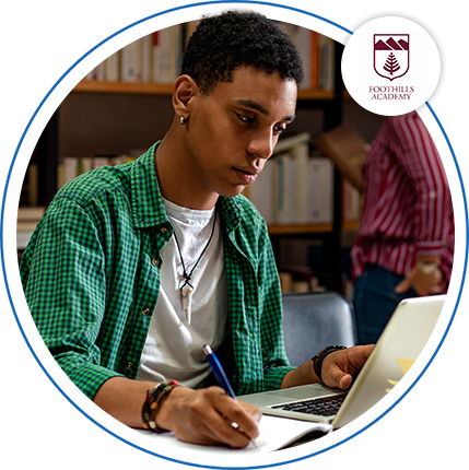 Image of a young man in a library on a laptop