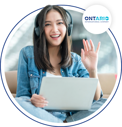 Image of a women smiling and waving with headphones on her head and a laptop in her lap.