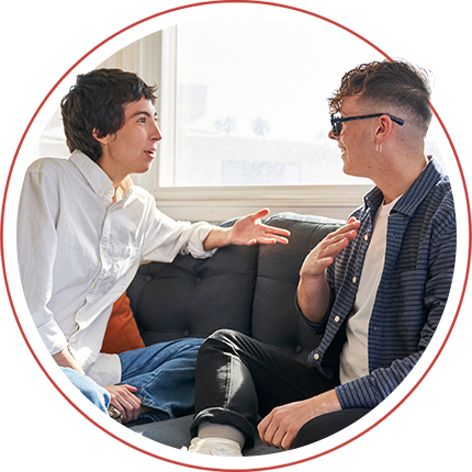 two men sat by a window chatting