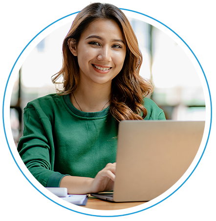 Woman working at a laptop looking up and smiling at the camera