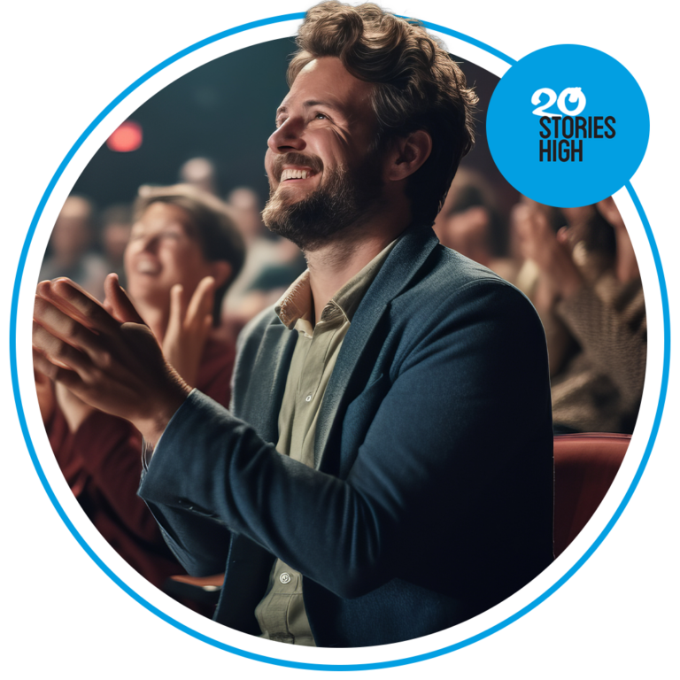 Image shows person clapping sitting in an audience